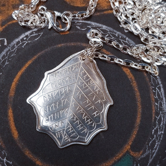 This Elvish Mithril Leaf of Spring Necklace is crafted in celebration of The Lord of the Rings by J. R. R. Tolkien. The leaf-shaped coin is struck from solid silver, measures 2.7 cm in diameter, and weighs about 6.5 grams. Includes a 30" antique bronze cable chain with clasp. Coin artwork by Greg Franck-Weiby. Coins are struck one at a time in the USA using antique machinery and traditional coining techniques. A colorful description is included with history, translations, and facts about the coins.