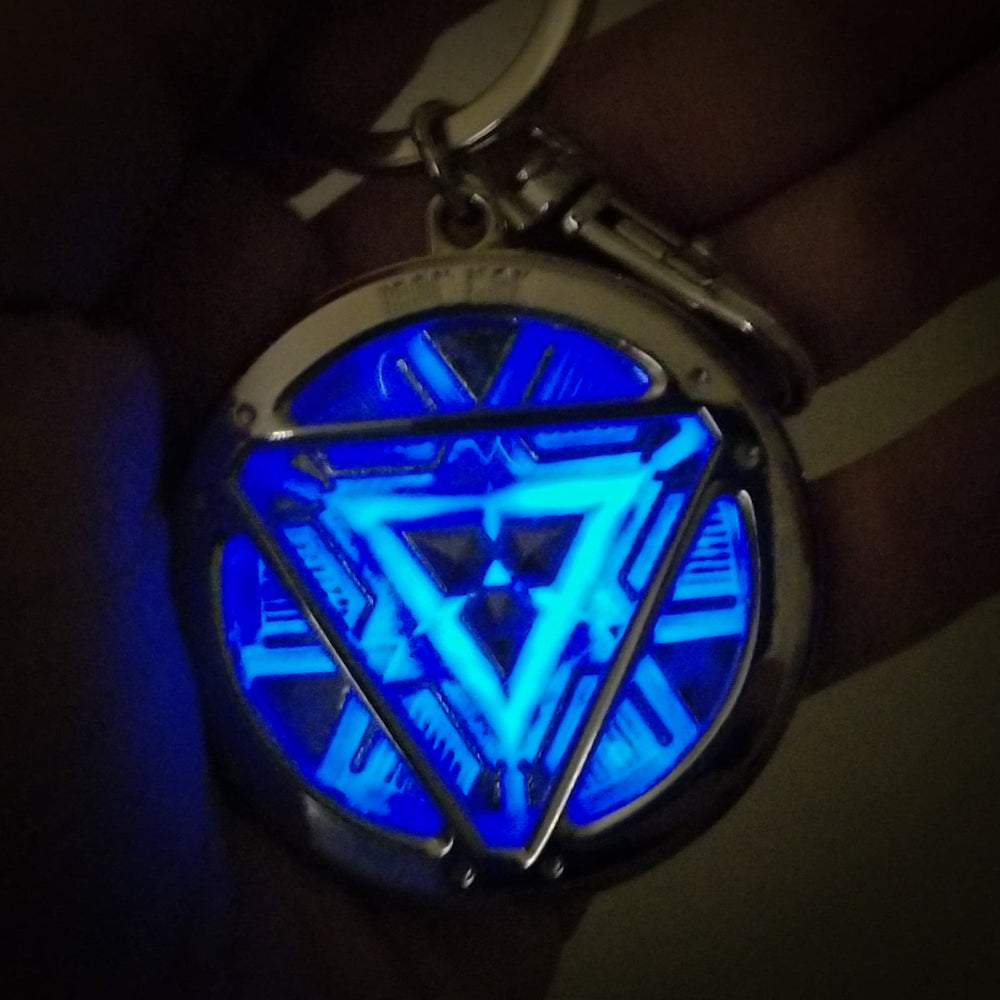 Iron Man Glow-In-The-Dark Pewter Arc Reactor Keychain.  In Celebration of Tony Stark’s Iron Man as seen in the Marvel Studios Avengers films, this oversize pewter Arc Reactor glow-in-the-dark metal keychain features the Arc Reactor powering Tony’s chest and power suit in Iron Man 3.  2 inches across & nearly 1/2 inch thick!  Features “Iron Man” logo on the back Includes stainless steel keyring and clip Blue Glow-in-the-Dark effect!  Carry your own Proof that Tony Stark Has a Heart