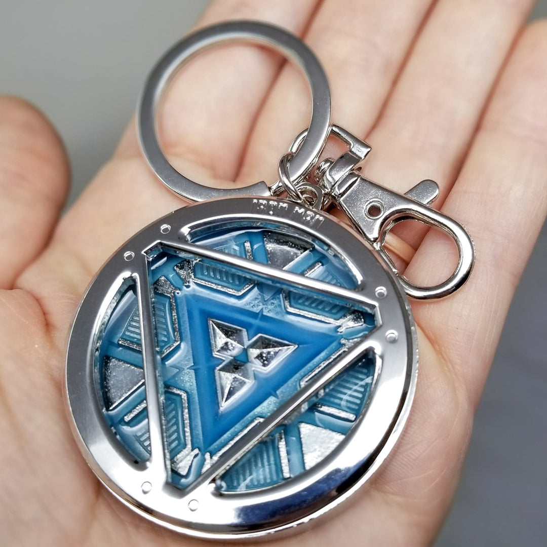 Iron Man Glow-In-The-Dark Pewter Arc Reactor Keychain.  In Celebration of Tony Stark’s Iron Man as seen in the Marvel Studios Avengers films, this oversize pewter Arc Reactor glow-in-the-dark metal keychain features the Arc Reactor powering Tony’s chest and power suit in Iron Man 3.  2 inches across &amp; nearly 1/2 inch thick!  Features “Iron Man” logo on the back Includes stainless steel keyring and clip Blue Glow-in-the-Dark effect!  Carry your own Proof that Tony Stark Has a Heart