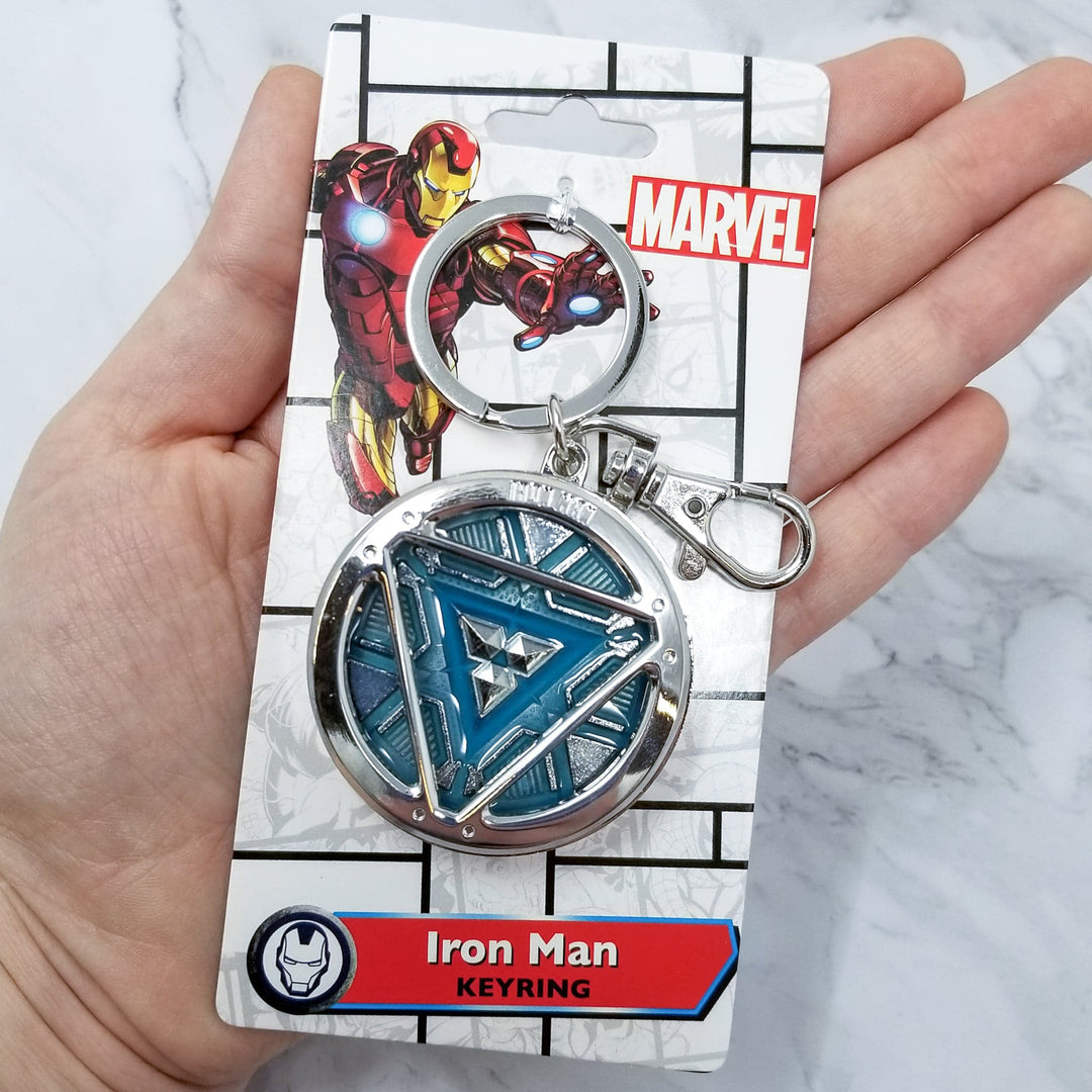 Iron Man Glow-In-The-Dark Pewter Arc Reactor Keychain.  In Celebration of Tony Stark’s Iron Man as seen in the Marvel Studios Avengers films, this oversize pewter Arc Reactor glow-in-the-dark metal keychain features the Arc Reactor powering Tony’s chest and power suit in Iron Man 3.  2 inches across &amp; nearly 1/2 inch thick!  Features “Iron Man” logo on the back Includes stainless steel keyring and clip Blue Glow-in-the-Dark effect!  Carry your own Proof that Tony Stark Has a Heart