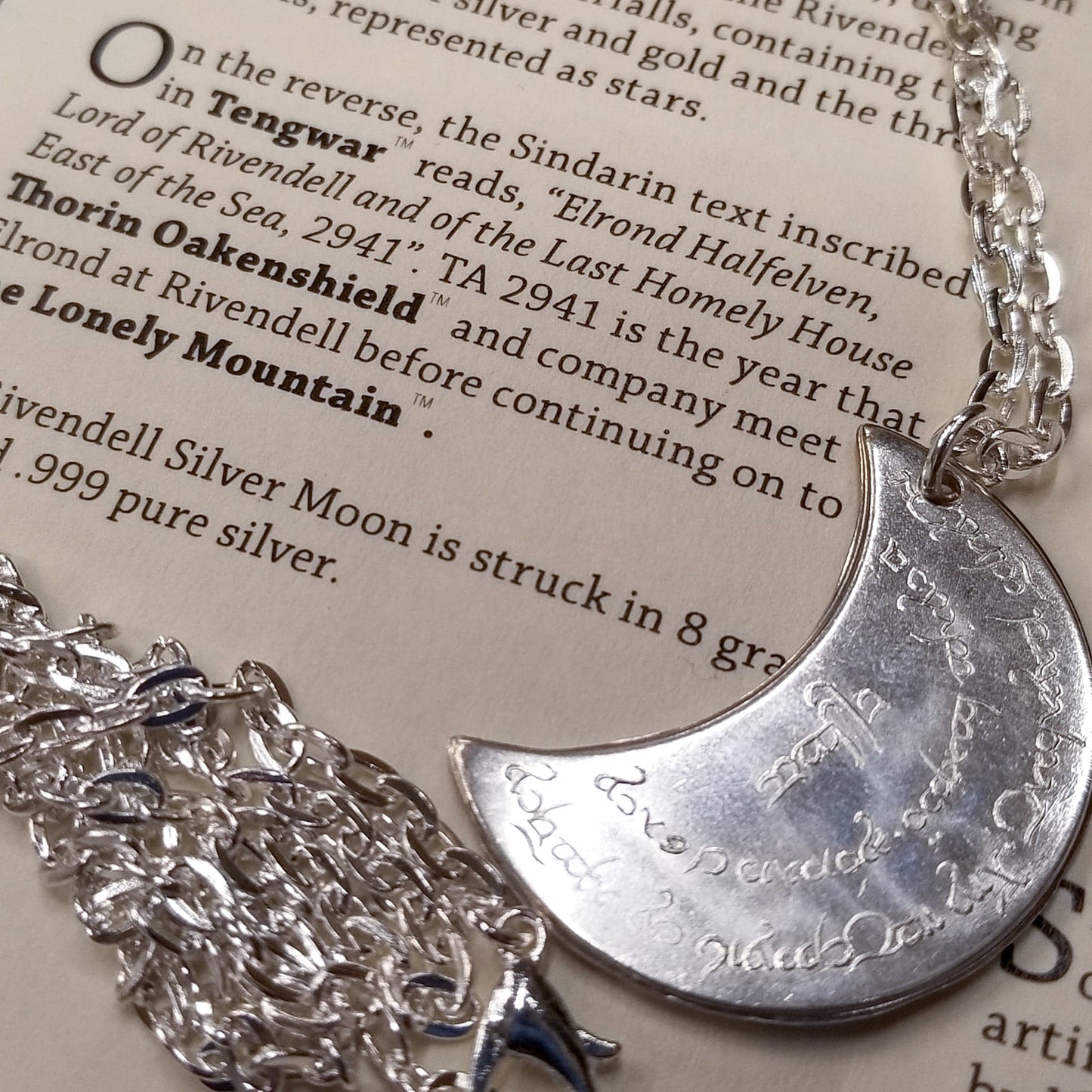 Elvish coin from Rivendell is shaped like a crescent moon. It depicts the valley containing the ancient trees of silver and gold and the three Silmarils, represented as stars. The text in Tengwar translates from Sindarin to Elrond Peredhil, Lord of Rivendell, The Last Homely House East of the Sea. It includes the date that Thorin and Company meet Elrond at Rivendell before continuing on to The Lonely Mountain.  This Rivendell Moon is crafted in celebration of The Lord of the Rings by J. R. R. Tolkien