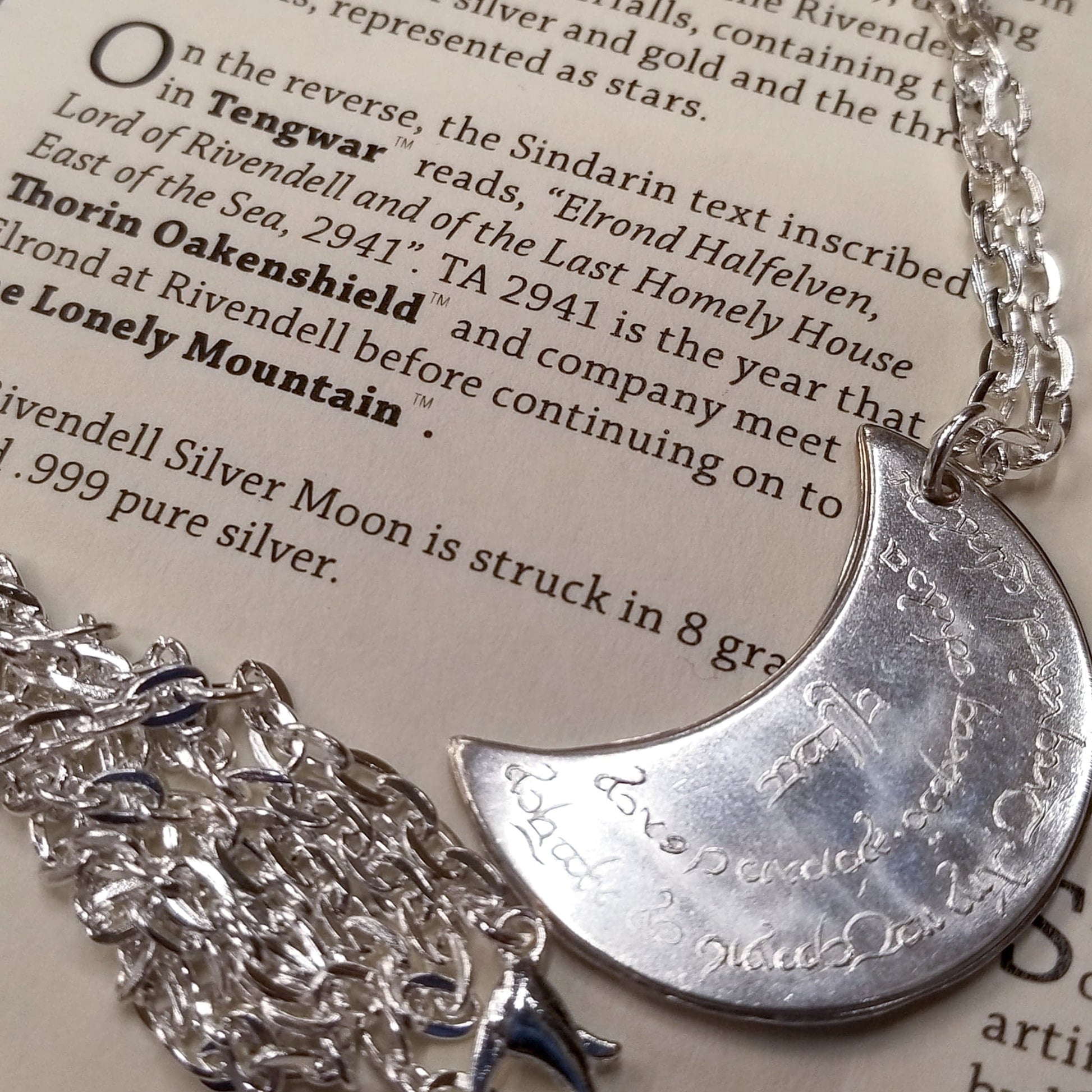 Elvish coin from Rivendell is shaped like a crescent moon. It depicts the valley containing the ancient trees of silver and gold and the three Silmarils, represented as stars. The text in Tengwar translates from Sindarin to Elrond Peredhil, Lord of Rivendell, The Last Homely House East of the Sea. It includes the date that Thorin and Company meet Elrond at Rivendell before continuing on to The Lonely Mountain.  This Rivendell Moon is crafted in celebration of The Lord of the Rings by J. R. R. Tolkien