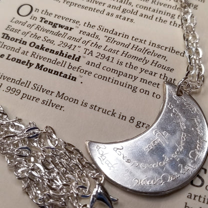 Elvish coin from Rivendell is shaped like a crescent moon. It depicts the valley containing the ancient trees of silver and gold and the three Silmarils, represented as stars. The text in Tengwar translates from Sindarin to Elrond Peredhil, Lord of Rivendell, The Last Homely House East of the Sea. It includes the date that Thorin and Company meet Elrond at Rivendell before continuing on to The Lonely Mountain.  This Rivendell Moon is crafted in celebration of The Lord of the Rings by J. R. R. Tolkien