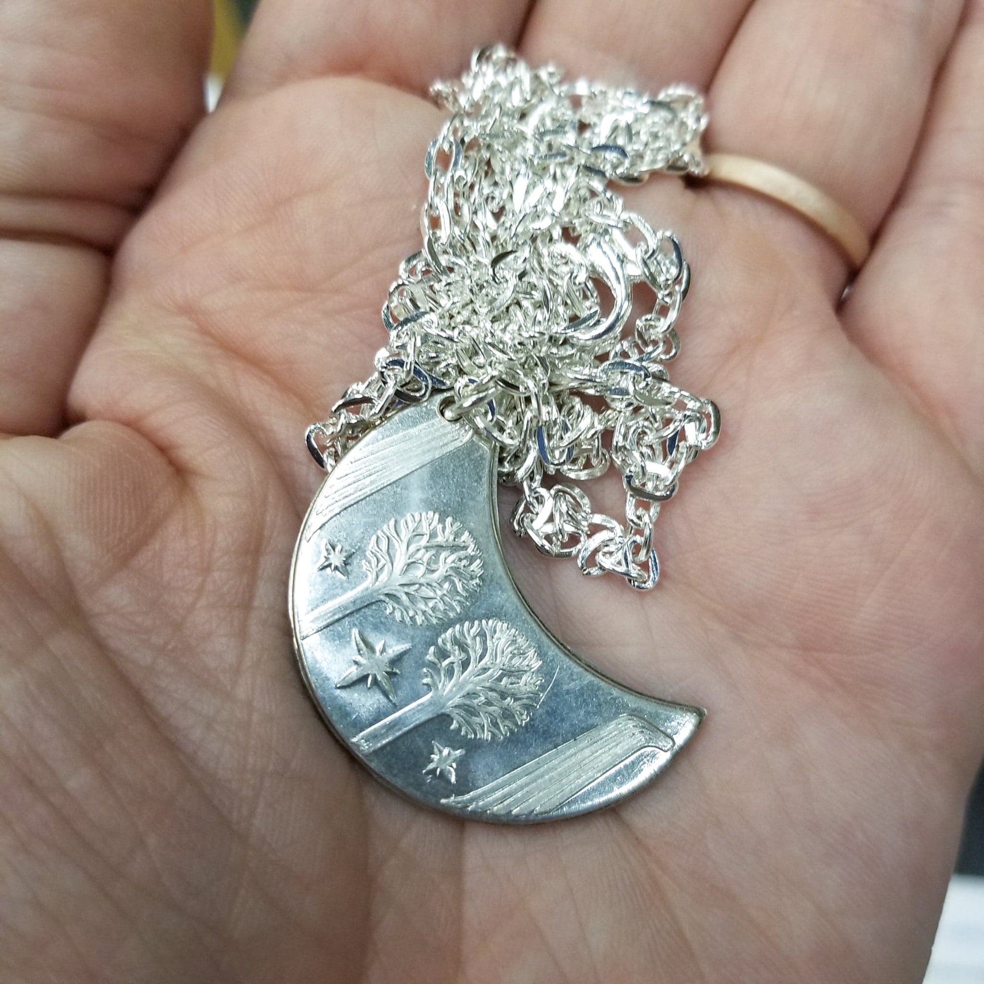 Elvish coin from Rivendell is shaped like a crescent moon. It depicts the valley containing the ancient trees of silver and gold and the three Silmarils, represented as stars. The text in Tengwar translates from Sindarin to Elrond Peredhil, Lord of Rivendell, The Last Homely House East of the Sea. It includes the date that Thorin and Company meet Elrond at Rivendell before continuing on to The Lonely Mountain.  This Rivendell Moon is crafted in celebration of The Lord of the Rings by J. R. R. Tolkien