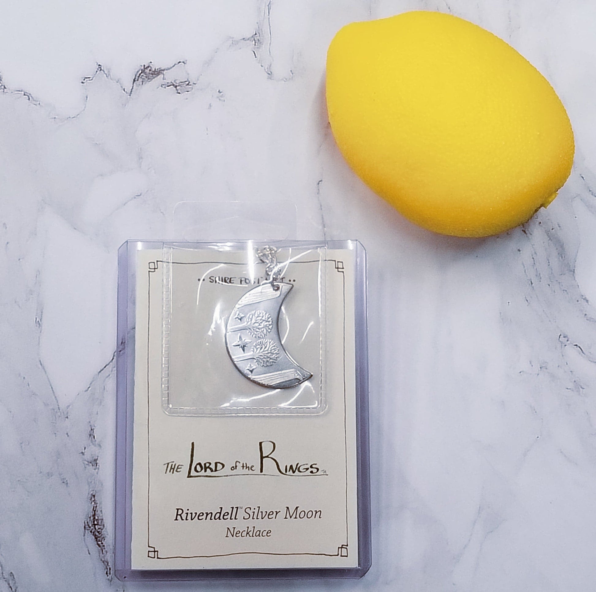 Elvish coin from Rivendell is shaped like a crescent moon. It depicts the valley containing the ancient trees of silver and gold and the three Silmarils, represented as stars. The text in Tengwar translates from Sindarin to Elrond Peredhil, Lord of Rivendell, The Last Homely House East of the Sea. It includes the date that Thorin and Company meet Elrond at Rivendell before continuing on to The Lonely Mountain.  This Rivendell Moon is crafted in celebration of The Lord of the Rings by J. R. R. Tolkien