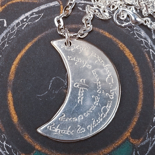 Elvish coin from Rivendell is shaped like a crescent moon. It depicts the valley containing the ancient trees of silver and gold and the three Silmarils, represented as stars. The text in Tengwar translates from Sindarin to Elrond Peredhil, Lord of Rivendell, The Last Homely House East of the Sea. It includes the date that Thorin and Company meet Elrond at Rivendell before continuing on to The Lonely Mountain.  This Rivendell Moon is crafted in celebration of The Lord of the Rings by J. R. R. Tolkien
